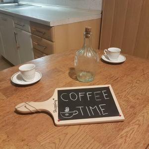 Una botella de café en una mesa con dos tazas. en Miklavževa hiša with a bread oven, en Železniki