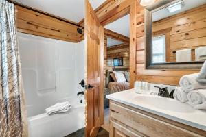 Un baño con bañera, lavabo y espejo. en Alpine Splendor Family Game Room Views Hot Tub, en Sevierville 119 fotos más
