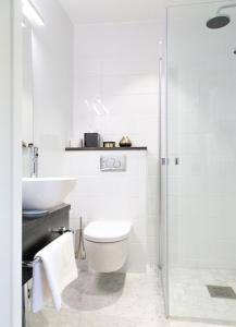 a white bathroom with a toilet and a sink at Continental du Sud in Ystad