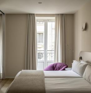Un dormitorio con una cama grande y una ventana en The Passage Apartments, en San Sebastián