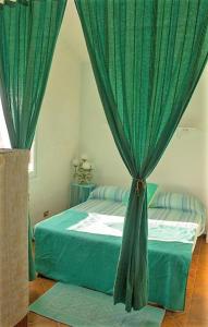 カンニジョネにあるResidenza Mediterraneaのベッドルーム1室(緑のカーテン付きのベッド1台付)