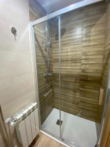um chuveiro com uma porta de vidro na casa de banho em El Capricho em Siero