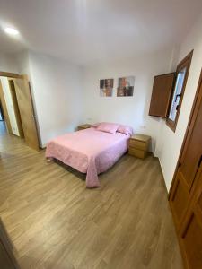 a bedroom with a pink bed and a wooden floor at El Capricho in Siero