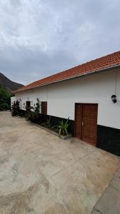 a white building with brown doors and a driveway at Kaza Ladera in Seladinha