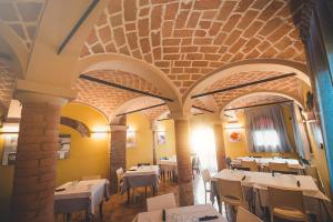 un ristorante con tavoli e sedie bianchi e un soffitto in mattoni di Agriturismo La Sapienza a Monestirolo