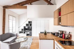a kitchen with white walls and wooden cabinets at Tourville - Très beau studio - Bail mobilité in Paris