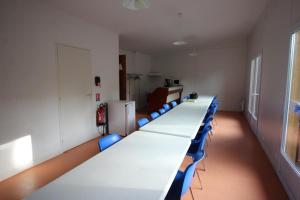 una sala de conferencias con mesas largas y sillas azules en Le mas - gite n°5 en Vaulry