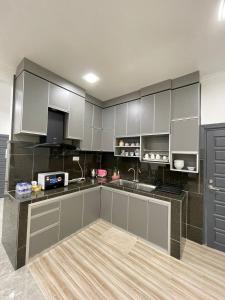uma cozinha com armários brancos e uma bancada em Aainaa Villa Homestay em Pasir Mas