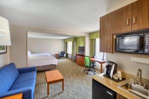 a hotel room with a bed and a living room at Holiday Inn Express Hotel & Suites Raleigh North - Wake Forest, an IHG Hotel in Wake Forest