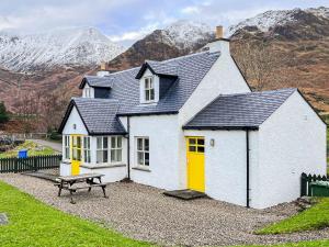 a white house with yellow doors and a picnic table at The Old Post Office in Arnisdale