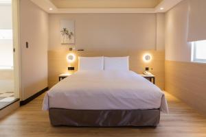 um quarto com uma grande cama branca e duas mesas em 旅居文旅板橋驛站-湳雅夜市館Hub Hotel Banqiao inn-Nanya Night Market Branch em Taipei