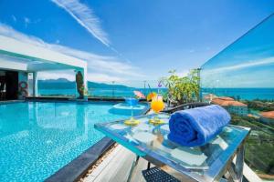 a villa with a pool and a table with a towel at Sea Phoenix Hotel Da Nang in Danang