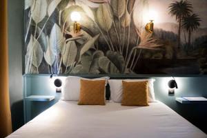 坎城的住宿－戛納中心普魯伊別墅酒店，卧室配有一张大床,墙上挂有绘画作品