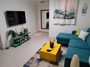 ein Wohnzimmer mit einem blauen Sofa und einem gelben Couchtisch in der Unterkunft Pura vida in Aschkelon