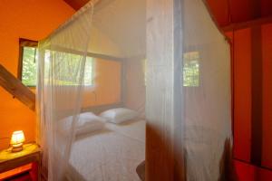 een slaapkamer met een wit hemelbed en een raam bij Parc de vacances La Draille in Souillac