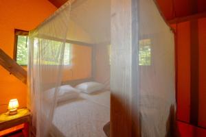 1 dormitorio con cama blanca con dosel y ventana en Parc de vacances La Draille en Souillac