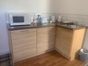 a kitchen with a microwave and a sink at Inverness City studio apartment sleeps 2 in Dalneigh