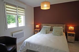 1 dormitorio con 1 cama blanca con silla y ventanas en Les cypres, en Magnac-Bourg