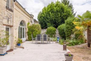 eine Terrasse mit Stühlen und Bäumen sowie ein Gebäude in der Unterkunft Maison Meslaie - Maison pour 8 avec piscine in Beaumont-en-Véron