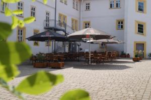 a patio with tables and umbrellas in front of a building at Schlosshotel am Hainich in Behringen