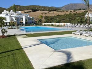 a swimming pool with chairs and a resort at Al-1103 Estepona - Apartment - Alcazaba Lagoon in Estepona