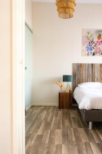 a bedroom with white walls and a bed with wood floors at Hoeve de Binnenplaets Schimmert in Schimmert