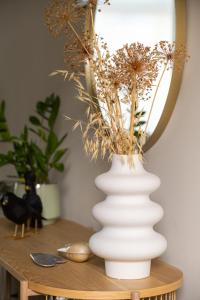 un jarrón blanco con flores en una mesa en Hoeve de Binnenplaets Schimmert en Schimmert