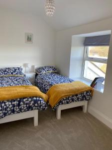 sypialnia z 2 łóżkami i oknem w obiekcie Rainbow Cottage w mieście Helston