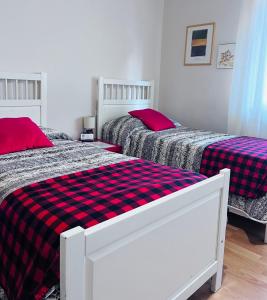 2 Betten in einem Schlafzimmer mit roter und schwarzer karierter Bettwäsche in der Unterkunft Bed&breakfast Benedetta in Cantagrillo