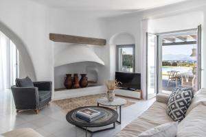 a living room with a couch and a tv at Aqua Breeze Villas on the beach in Plaka