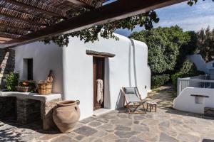 a white house with a chair and a vase on a patio at Aqua Breeze Villas on the beach in Plaka