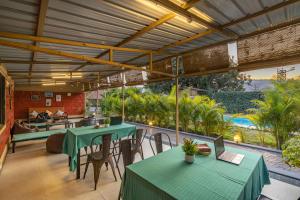 patio z zielonymi stołami i krzesłami oraz basenem w obiekcie Zostel Kolad w mieście Kolad