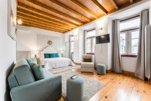 a living room with a blue couch and a bed at R3 Service - Five Senses in Coimbra in Coimbra