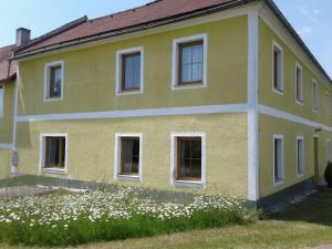 a yellow house with white windows and a field of flowers at Naturfreunde Alpenvorland in Kilb