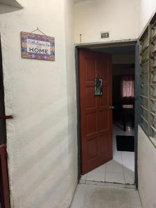een deur naar een huis met een bord aan de muur bij JoeRos Homestay in Shah Alam
