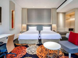 a hotel room with two beds and a table at Novotel Palembang in Palembang