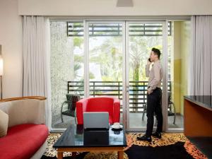 a man talking on a cell phone in a hotel room at Novotel Palembang in Palembang