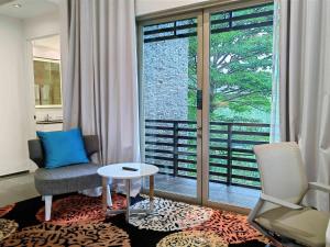 a living room with a chair and a table and a window at Novotel Palembang in Palembang