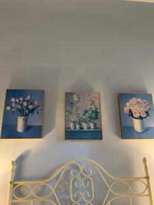 three pictures of flowers in vases on a wall at Santa Marija House in Victoria