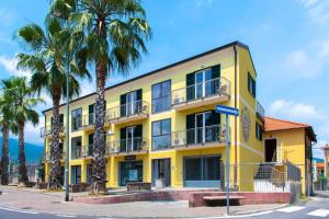 a yellow building with palm trees in front of it at Libeccio in Loano