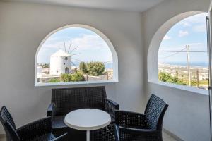 un restaurante con 2 ventanas y un molino de viento en Orizontes Hotel Santorini en Pirgos