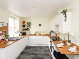a kitchen with white cabinets and a wooden counter top at Gwynant - Morfa Nefyn in Pwllheli