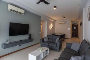 ein Wohnzimmer mit einem Sofa und einem Flachbild-TV in der Unterkunft Family Seaview Suite with 3 Rooms by The Only Bnb in Tanjong Tokong