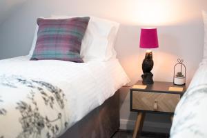 ein Bett mit einem Kissen und einer Lampe auf einem Nachttisch in der Unterkunft Moseley Gardens Fallowfield in Manchester