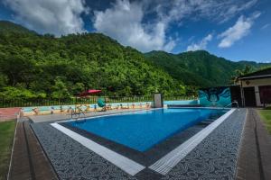 a swimming pool with a mountain in the background at DLS MJ River Resort, Rishikesh in Shivpuri