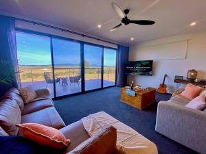 sala de estar con sofá y ventilador de techo en Wamoon Retreat - Luxe House, en Yanakie
