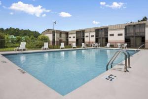a swimming pool with chairs and tables in a building at Days Inn by Wyndham Fayetteville-South/I-95 Exit 49 in Fayetteville