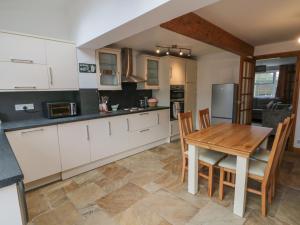 a kitchen with white cabinets and a wooden table at 3 Wilson Cottages in Ganton