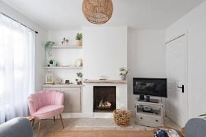 a living room with a pink chair and a fireplace at Seabreeze Cottage in Walmer