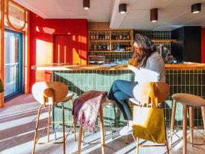 a woman sitting at a bar in a restaurant at ibis Styles Antibes in Antibes